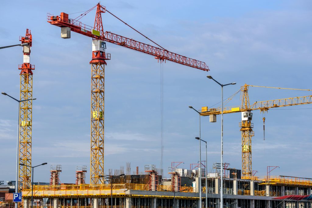 pexels photo 224924 224924 Multiple tower cranes working on a large construction site with blue sky backdrop.