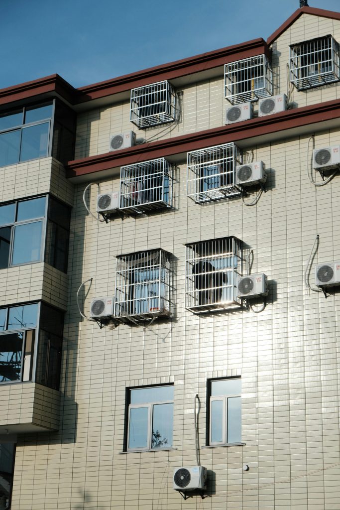 pexels photo 28492754 28492754 Exterior of a building with multiple air conditioners and window cages.